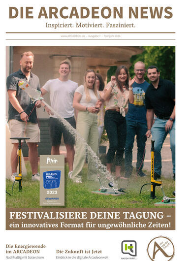 Eine Gruppe von sechs Personen steht im Freien und gießt Champagner in Gläser auf einem kleinen Ständer. Ein Festivalschild und ein Zeitschriften-Branding sind vorhanden.